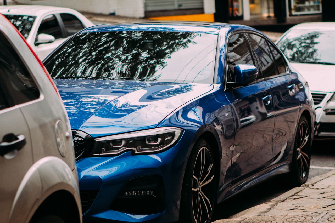 team-04 A vibrant blue luxury sedan parked on an urban street among cars.
